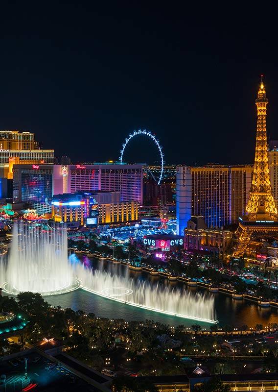 A view of the Las Vegas Strip, with a large fountain display below lit up buildings.