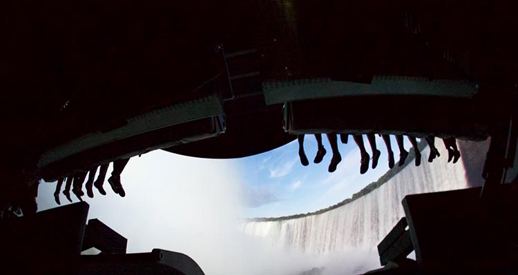 Feet dangle over the edge of the ride, a waterfall scene on the screen in front of them.