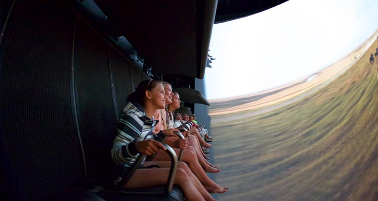 Riders on the flight ride hold onto their seats as they tilt forward on the ride.