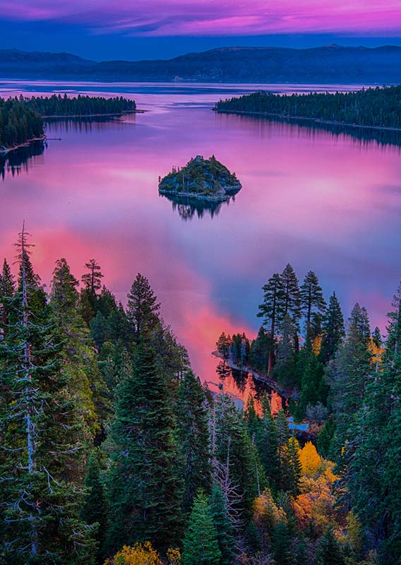 An aerial view of a lake, glowing with purple and pink light.